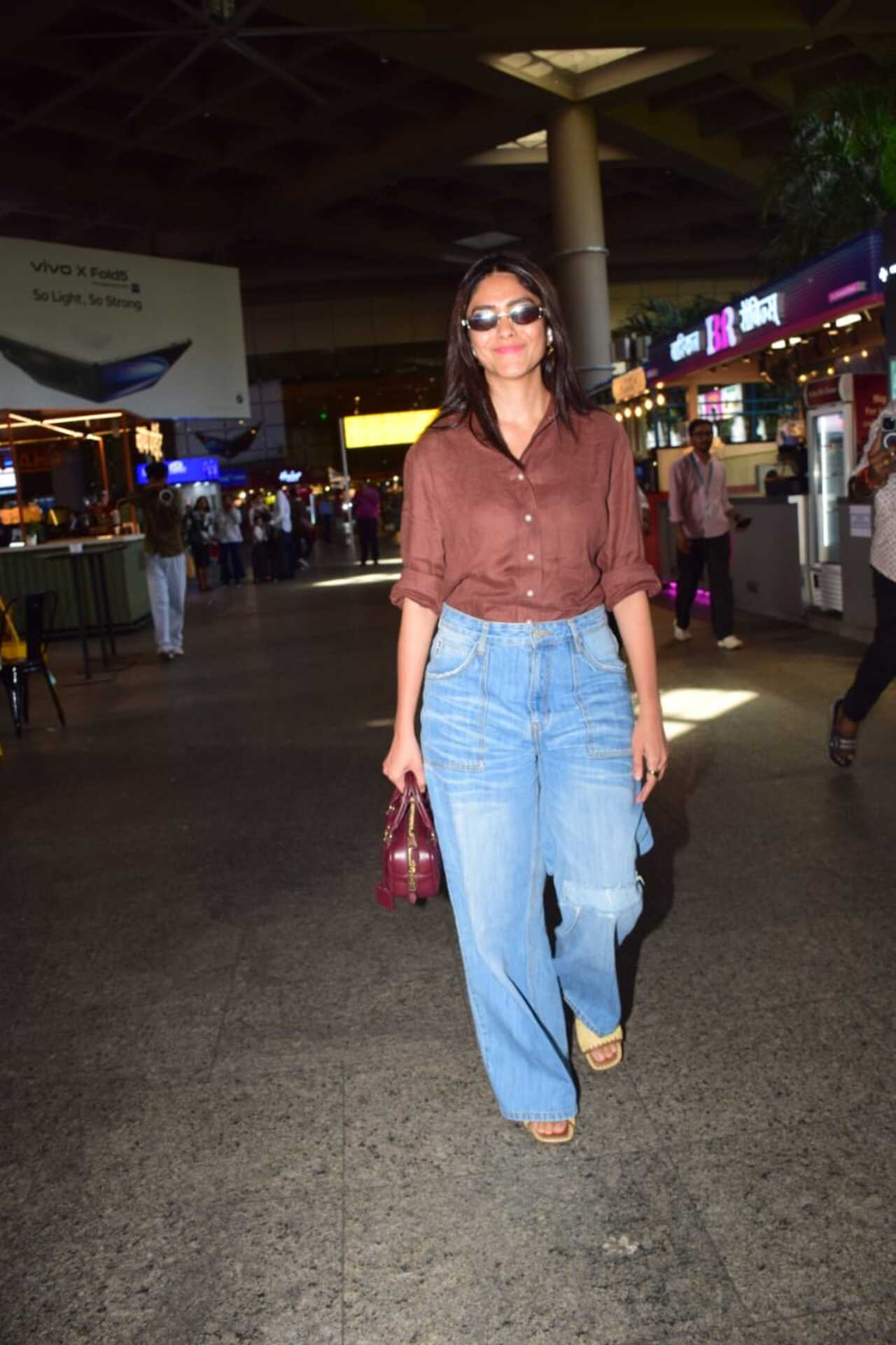 Mrunal Thakur was spotted at the airport sporting a brown shirt tucked in a blue jeans and sunglasses.